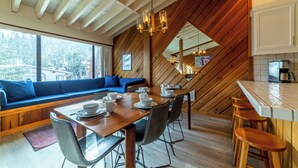 A dining area with a wooden table, chairs, and a blue sofa. - Walk to Ski Condo + Views, Fireplace, Jacuzzi 438 (Mammoth Lakes)
