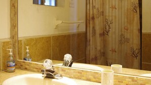 Une salle de bain avec deux lavabos, un miroir, une fenêtre et un rideau de douche.