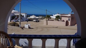 A view through an arched window of a coastal area with white buildings, a dirt road, and a clear blue sky. - Casa Bianchi Private Beach View Home Las Conchas (Puerto Peñasco)