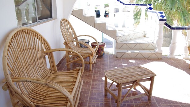 Un espace patio aménagé avec des meubles en osier et un sol carrelé.