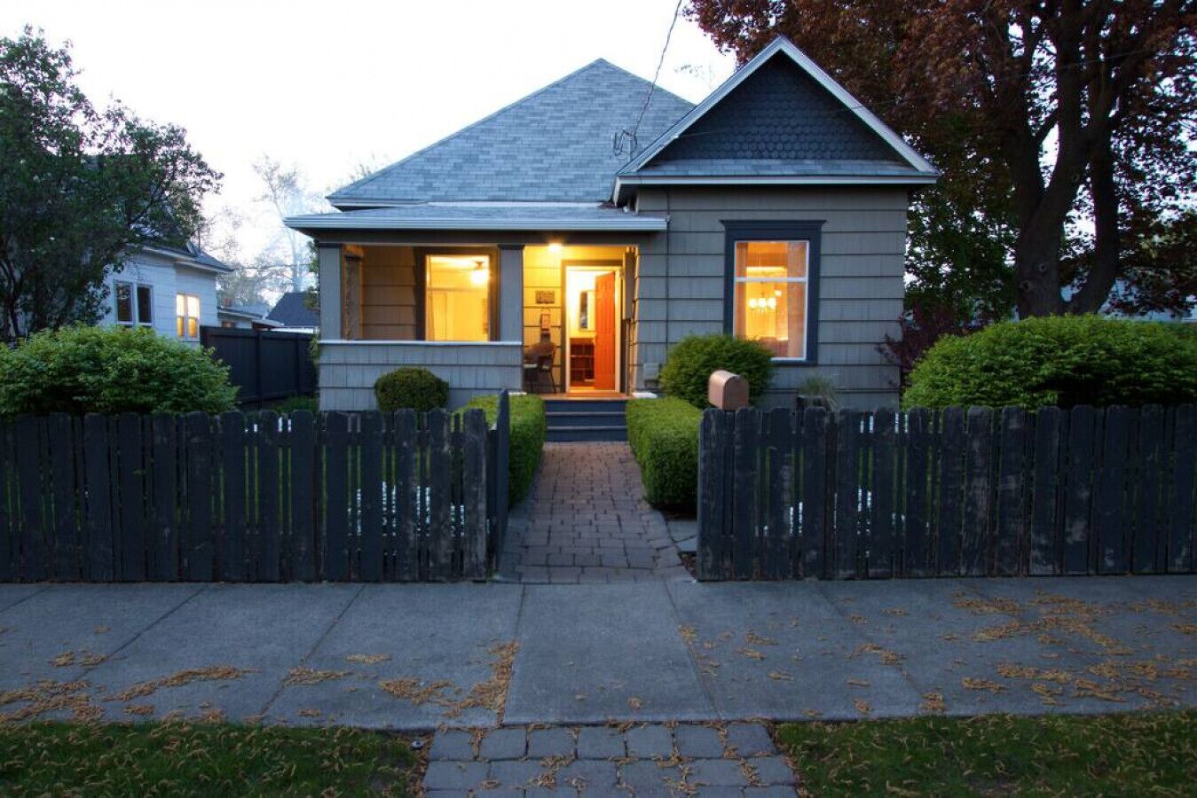 Une maison à deux étages avec un porche à l’avant, une clôture en piquets et une pelouse bien entretenue.