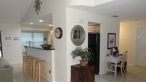 A spacious living area with a kitchen, dining area, and a small office space.