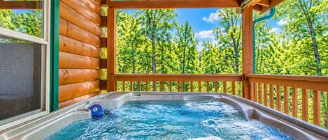 A hot tub with a digital display, surrounded by wooden deck and a view of a forest.
