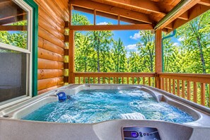 A hot tub with a digital display, surrounded by wooden deck and a view of a forest. - Glori's Retreat - $560 of FREE  tickets for each paid day (Pigeon Forge)