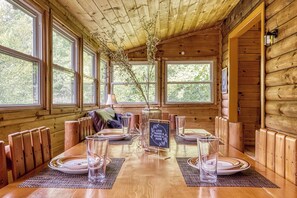 A wooden cabin with a dining table set for four, large windows, and a cozy interior. - Glori's Retreat - $560 of FREE  tickets for each paid day (Pigeon Forge)