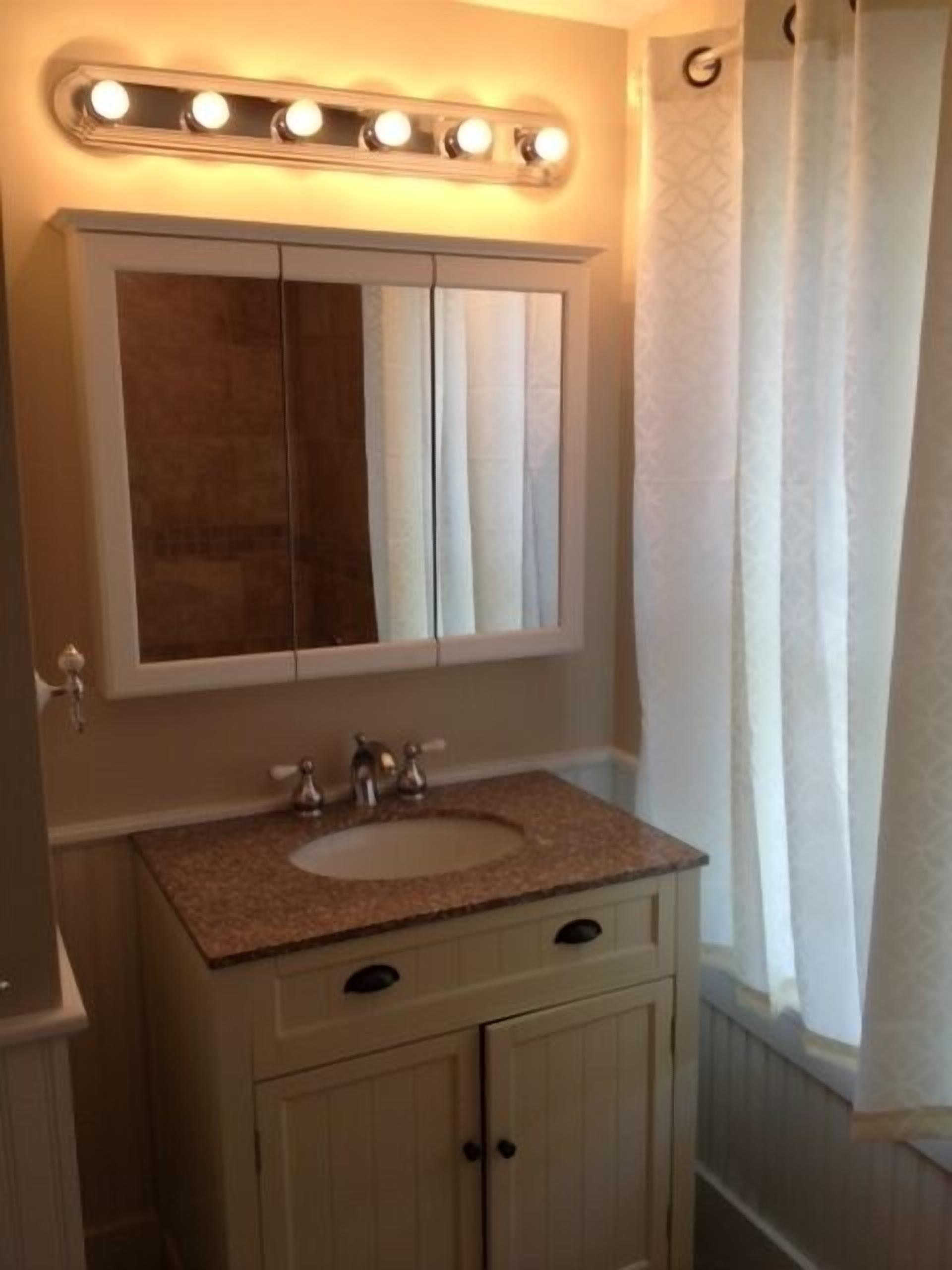 A bathroom with a vanity, a mirror, and a shower curtain.