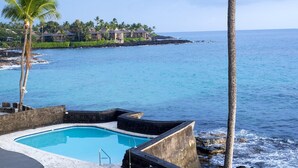 Une piscine offrant une vue dégagée sur l’océan, avec une zone de villégiature en arrière-plan.
