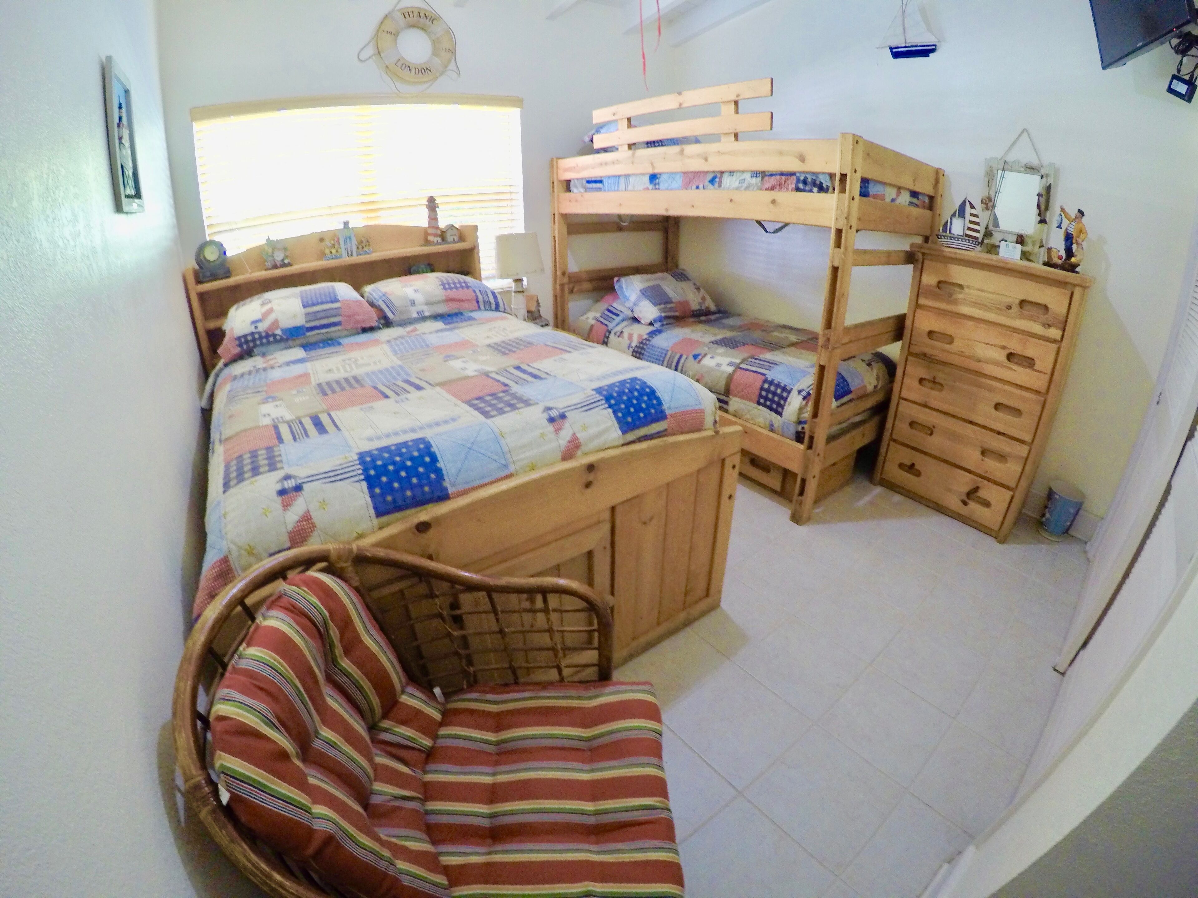 A bunk bed room with a wooden dresser and a small chair.