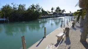 A dock extending into calm water with a paved walkway beside it. - DUPLEX IN DUCK KEY, 2 Bedroom /2 Bath  w/40' Dock,  Trailer Storage Incl. (Marathon)