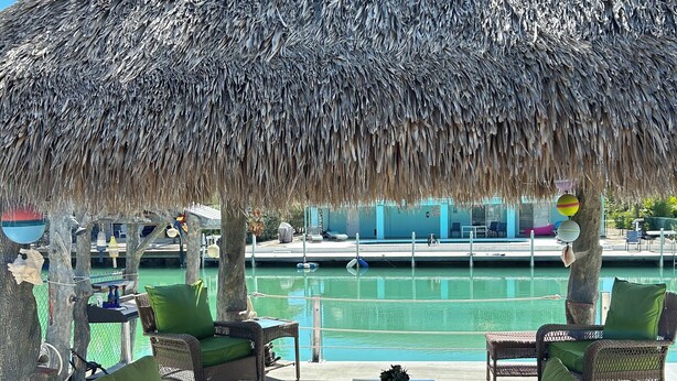 A thatched-roof outdoor seating area with wicker furniture and a view of a pool. - DUPLEX IN DUCK KEY, 2 Bedroom /2 Bath  w/40' Dock,  Trailer Storage Incl. (Marathon)