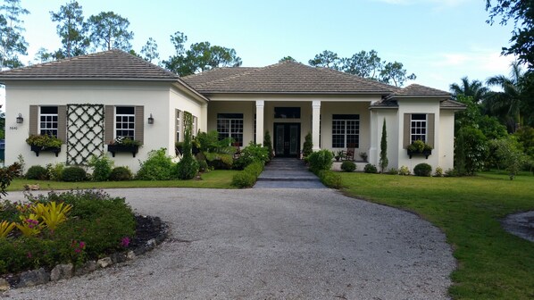 A two-story house with a gravel driveway leading to a front door.