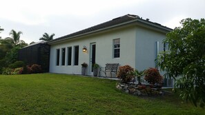A single-story house with a flat roof, a front porch with a bench, and a well-maintained lawn.