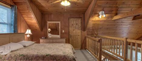 Une chambre à coucher comprenant un lit, une commode, un miroir, un ventilateur de plafond et un balcon avec une balustrade.