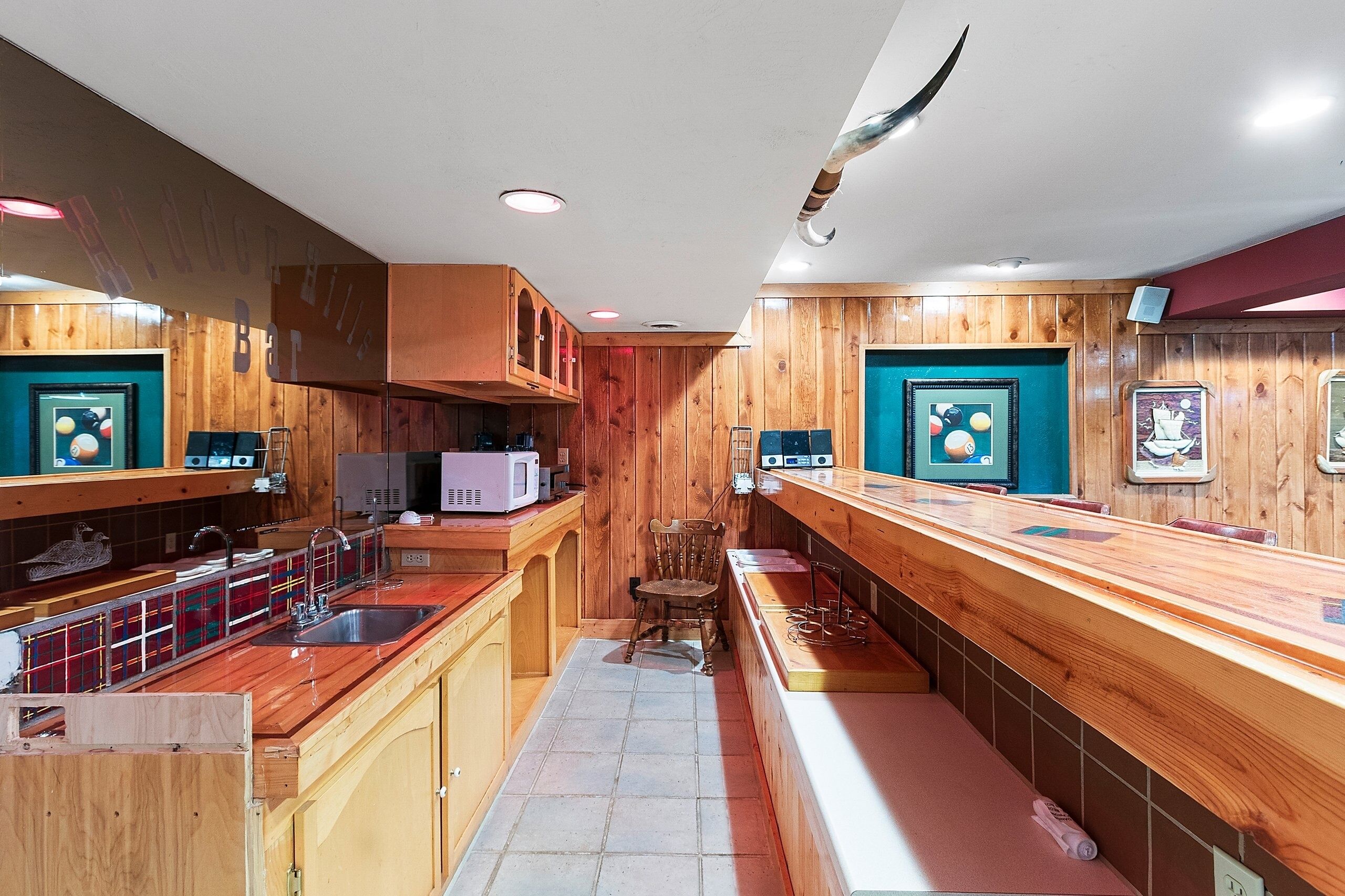 A narrow kitchen with wooden cabinets, a microwave, and a sink.