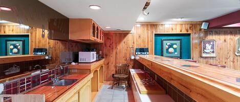 A narrow kitchen with wooden cabinets, a microwave, and a sink.