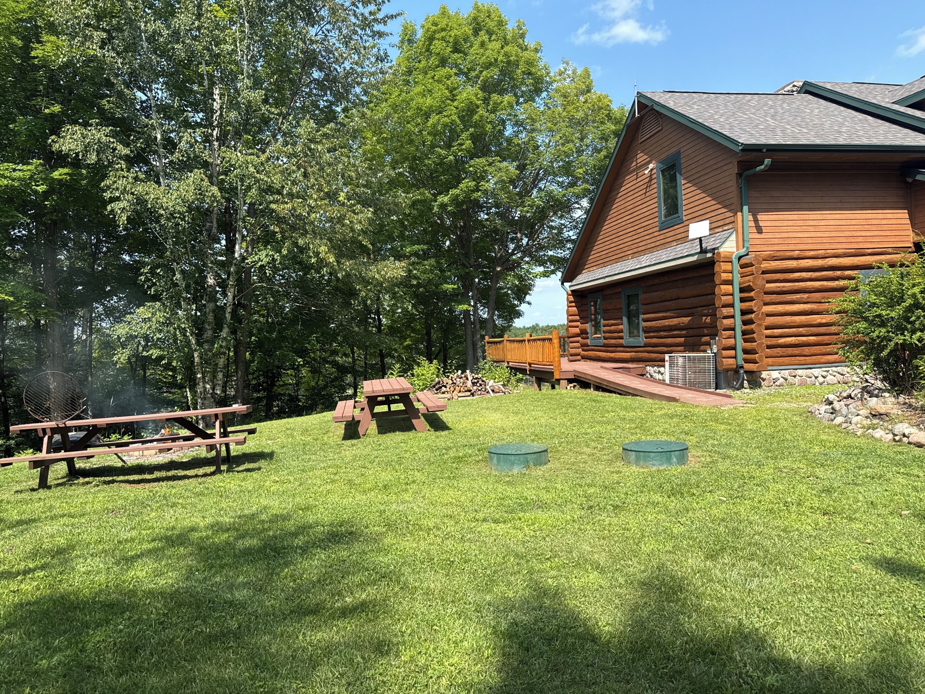 Eine Holzhütte mit einer Terrasse, umgeben von einem Rasen und Bäumen.