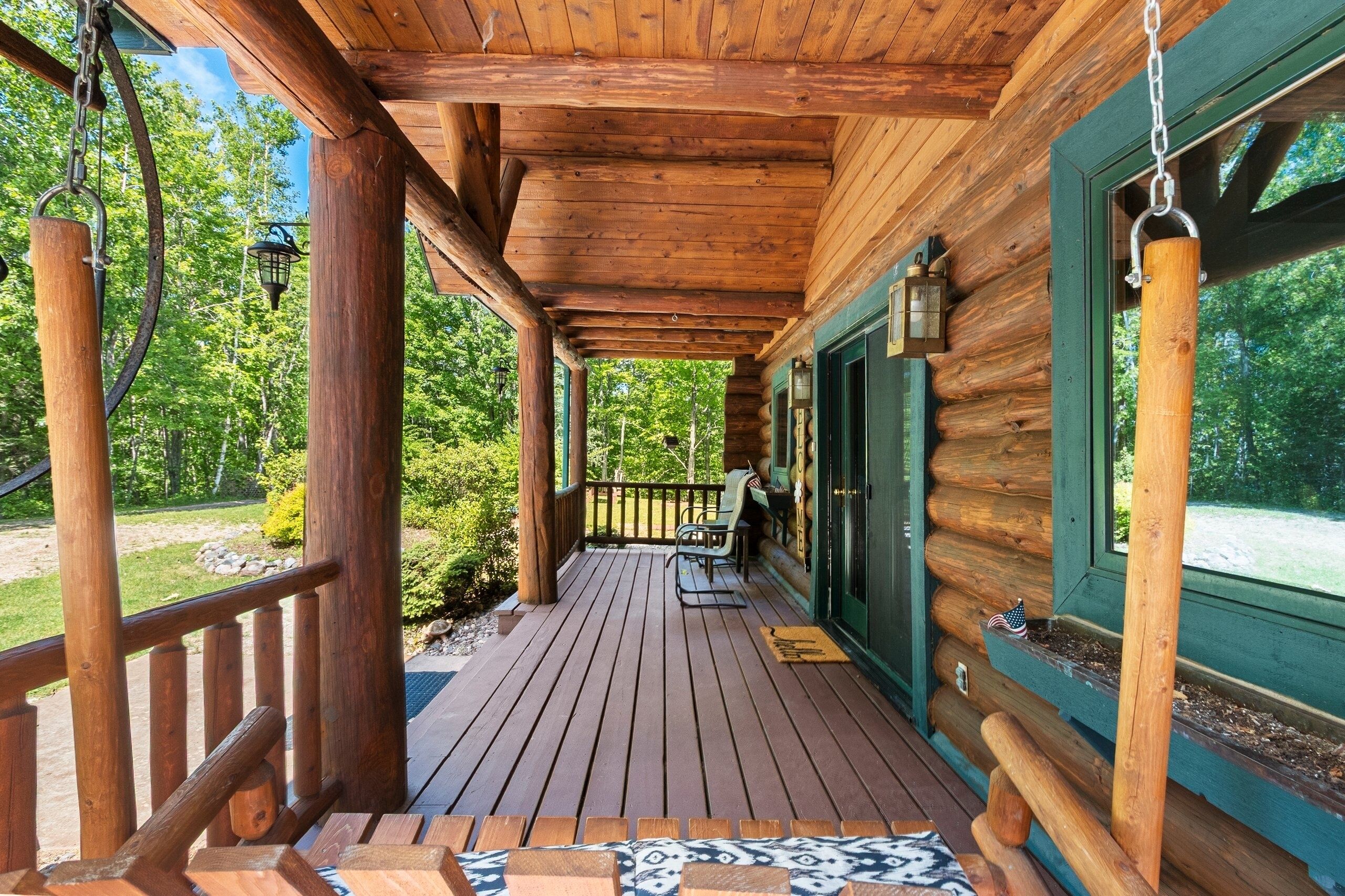 A wooden deck with a railing, a bench, and a door with a window.