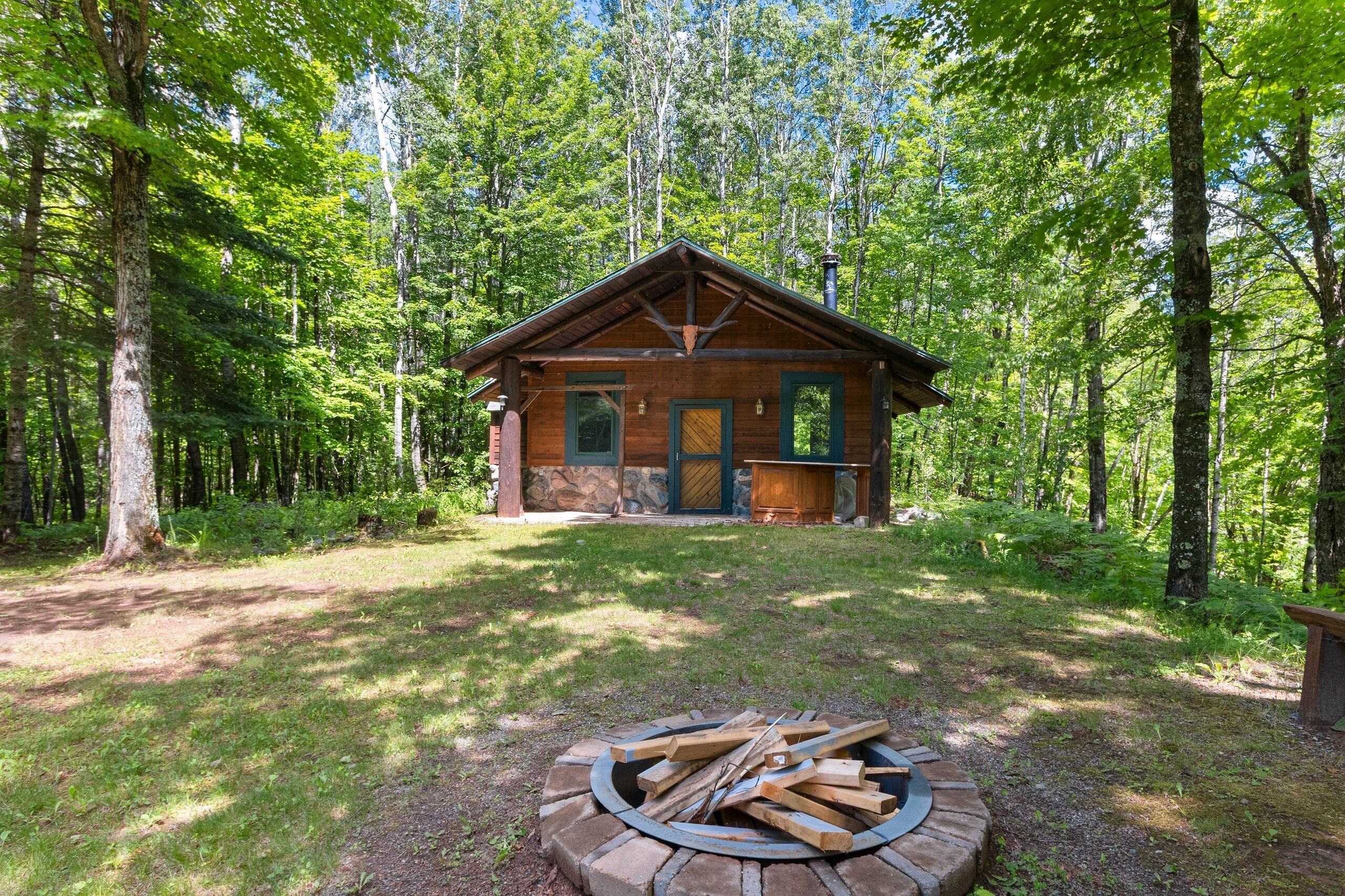 A cabin with a stone foundation, a wooden door, and a chimney.