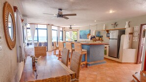 Une cuisine spacieuse avec un coin repas, de grandes fenêtres et une vue sur la mer.