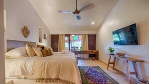 A bedroom with a bed, a desk, a chair, a ceiling fan, a TV, and a colorful rug. - One-of-a-Kind Akumal Villa – Eclectic Design, Pool & Private Lagoon Access (Akumal)