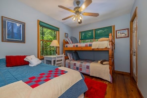 Enjoy a restful stay in this cozy room featuring a bunk bed, single bed, and desk with lamp.