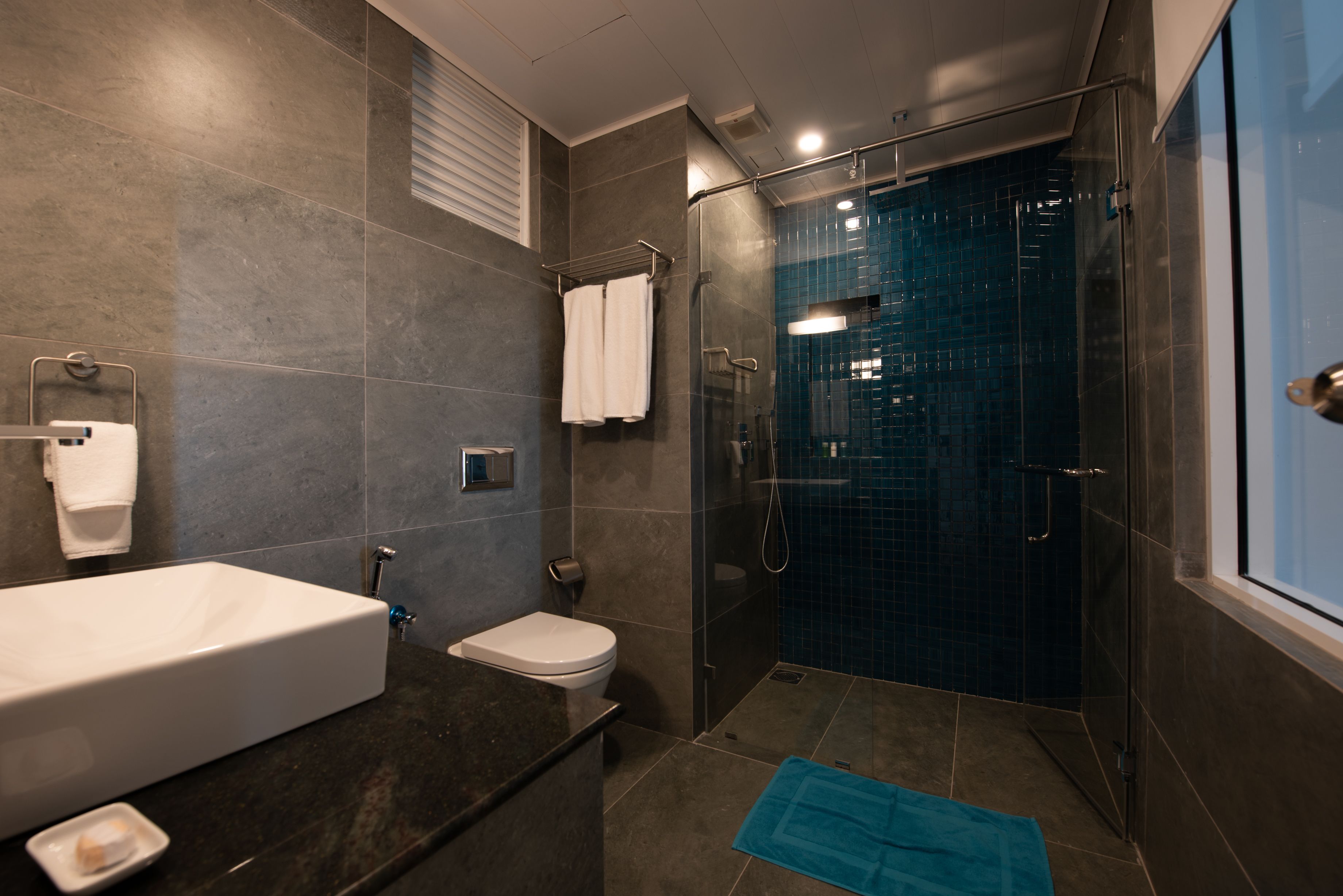 A modern bathroom with a bathtub, toilet, and glass-enclosed shower.