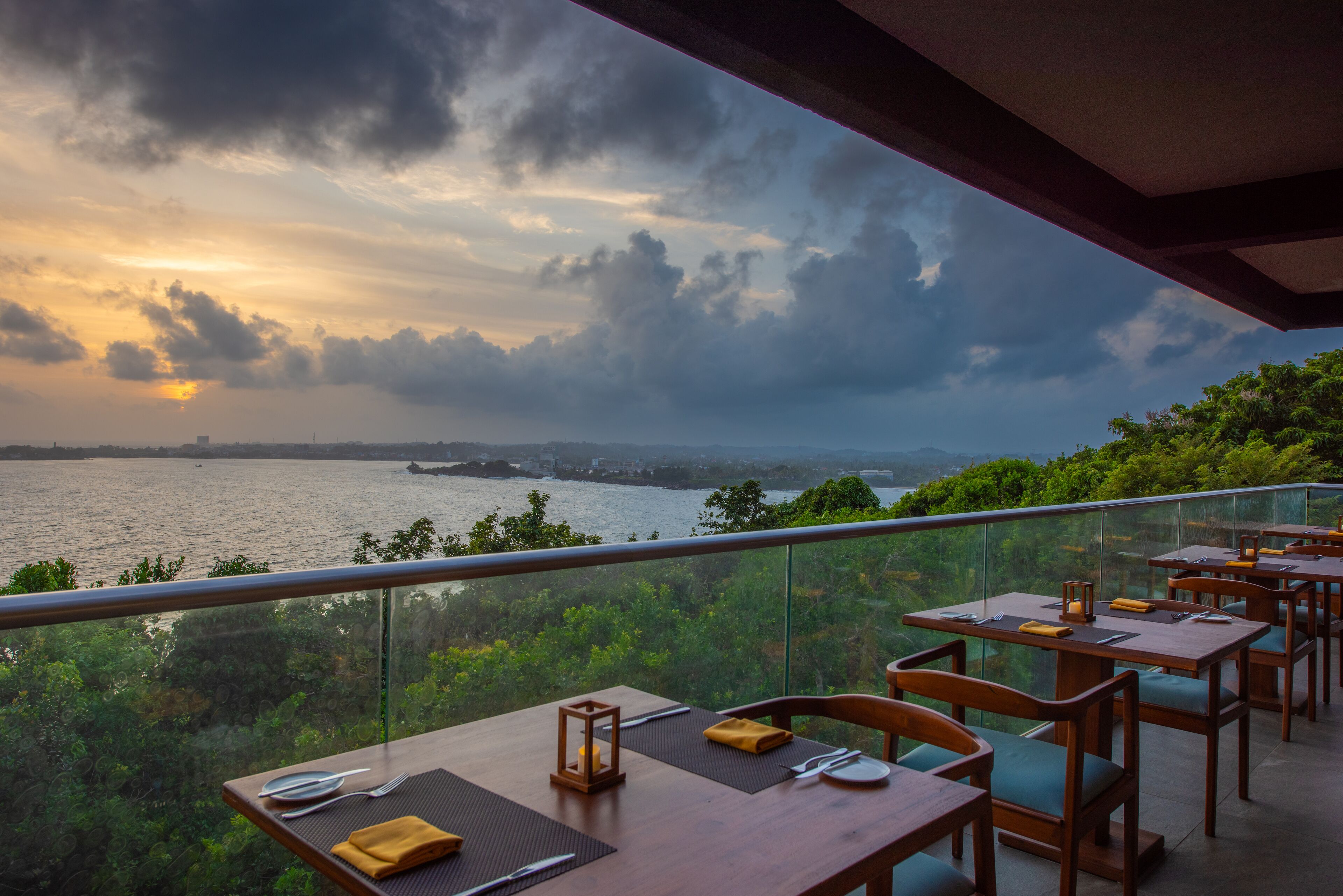 A restaurant with tables set for dining, overlooking a river and greenery.