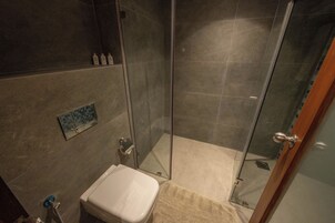 Un baño con cabina de ducha de vidrio, inodoro y lavabo.