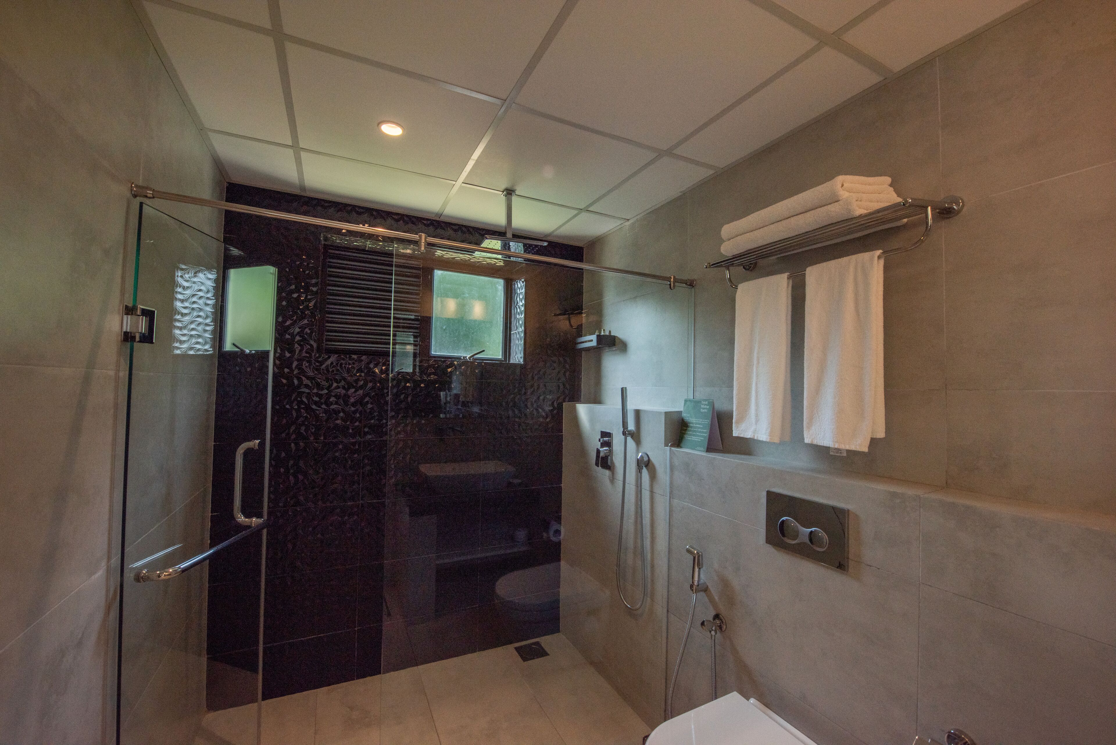 Un baño moderno con ducha de vidrio, inodoro separado y tocador con espejo.