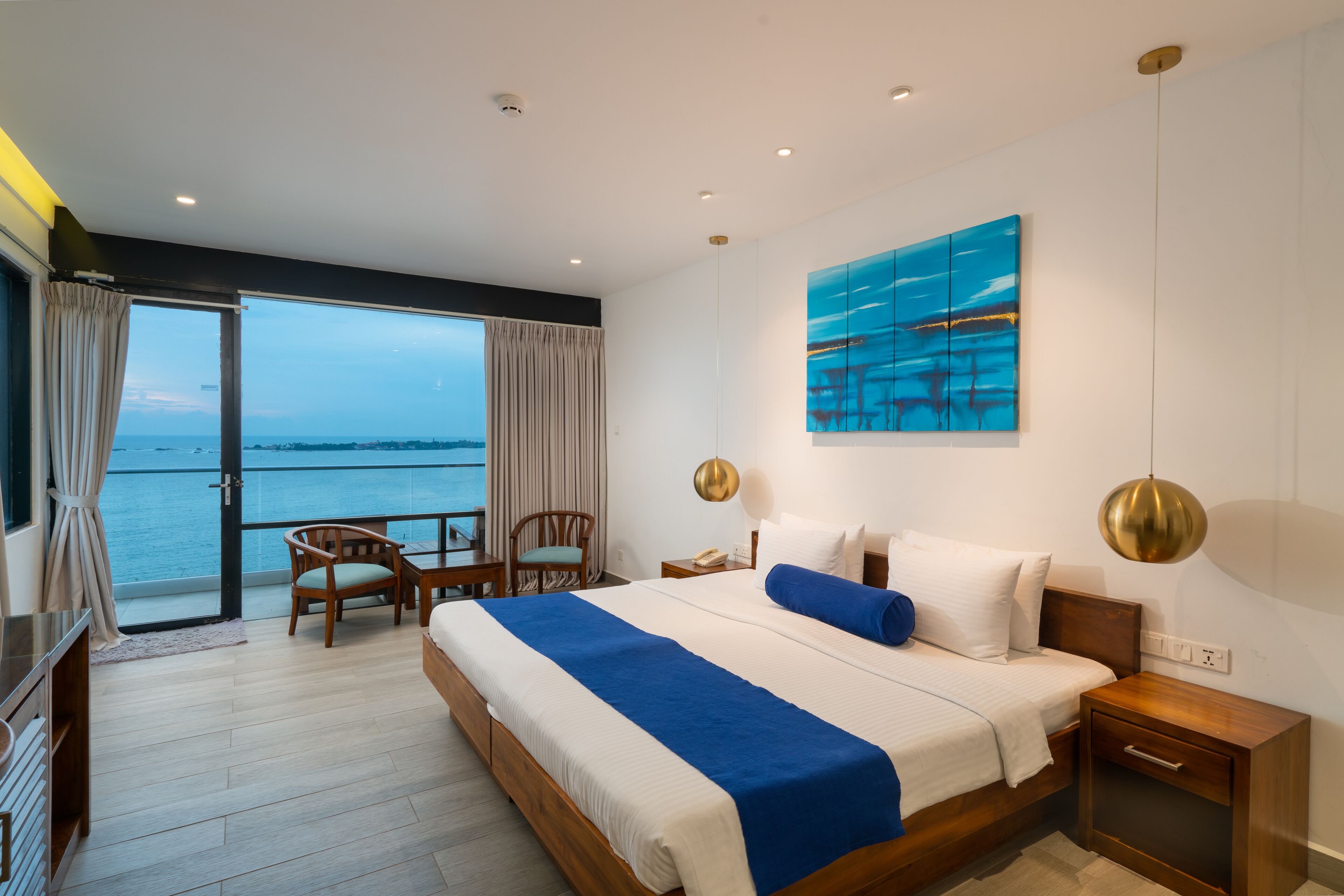 Habitación de hotel con una cama grande, un escritorio, una silla y vista al mar.