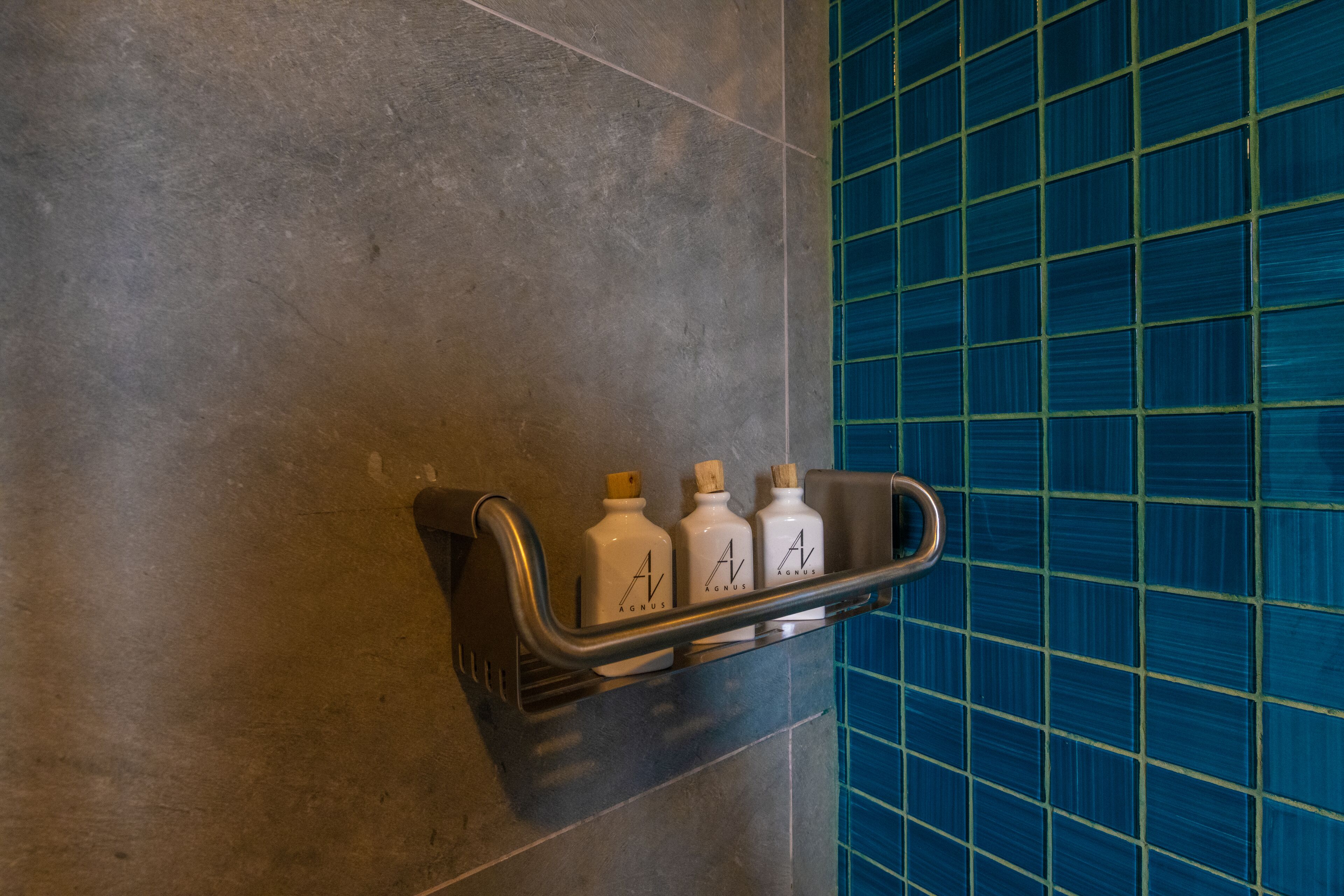A bathroom with a shelf holding three bottles of hand soap.