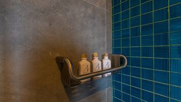 A bathroom with a shelf holding three bottles of hand soap.