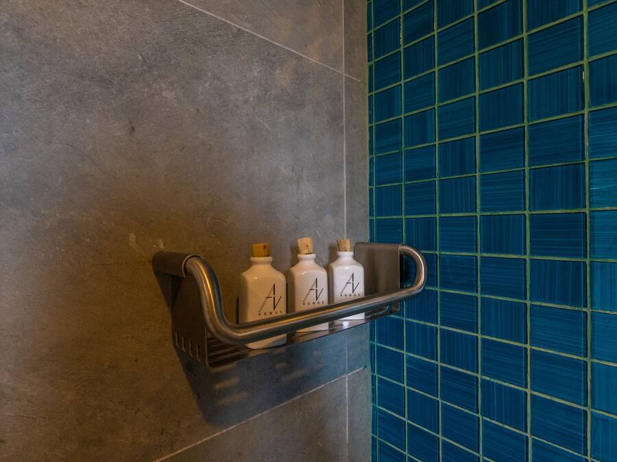 A bathroom with a shelf holding three bottles of hand soap.