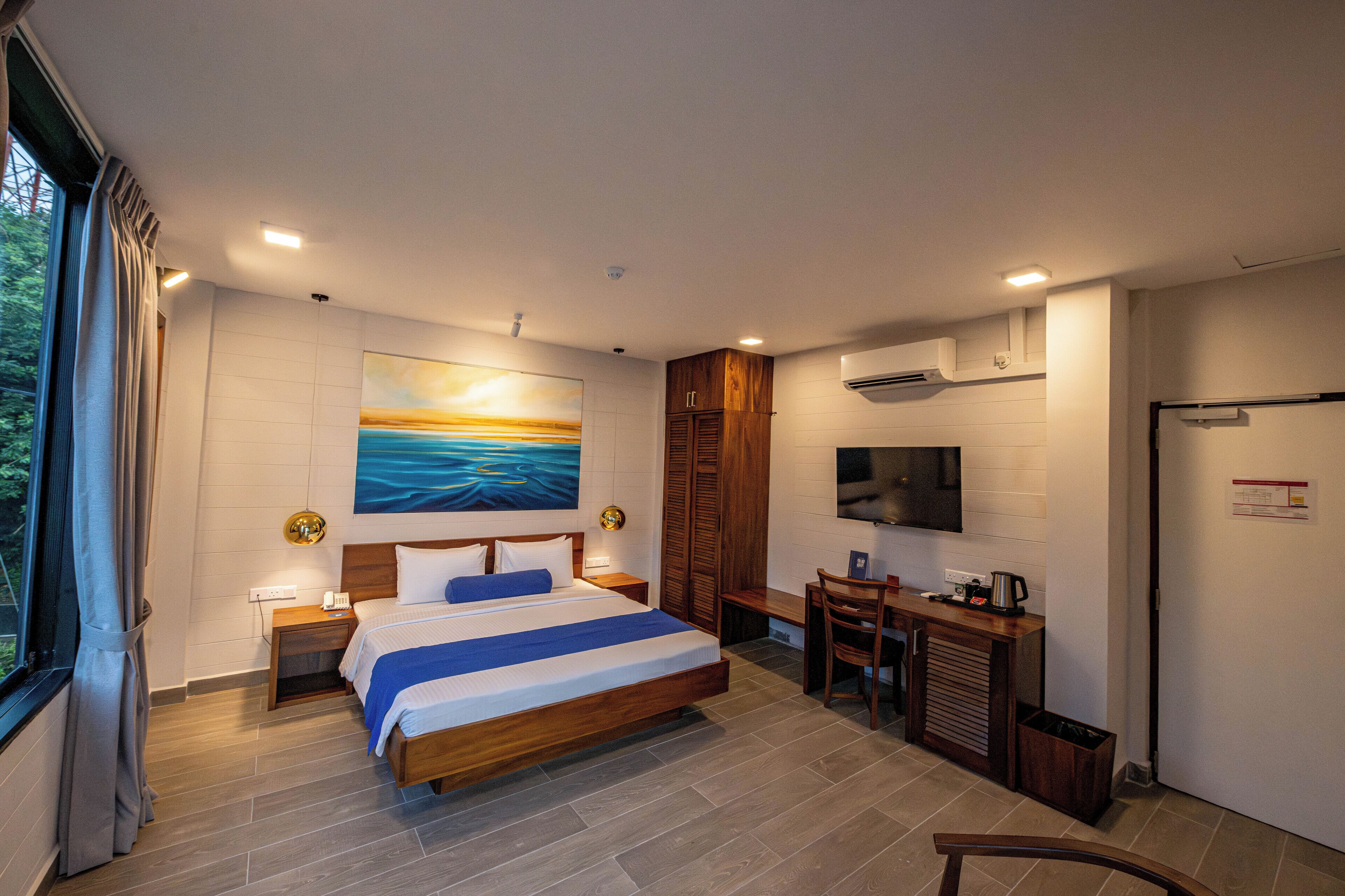 A modern hotel room with a large bed, a desk, a chair, and a TV.