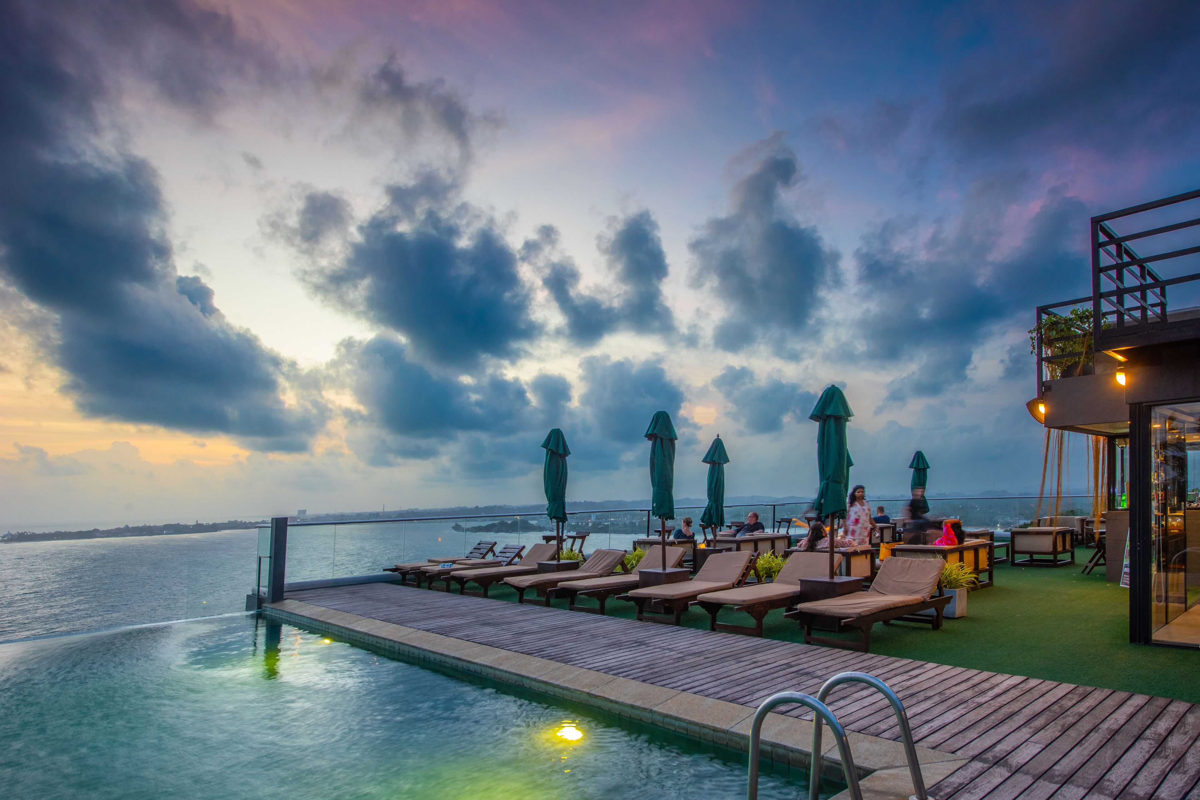 A poolside area with lounge chairs and umbrellas, overlooking a body of water.