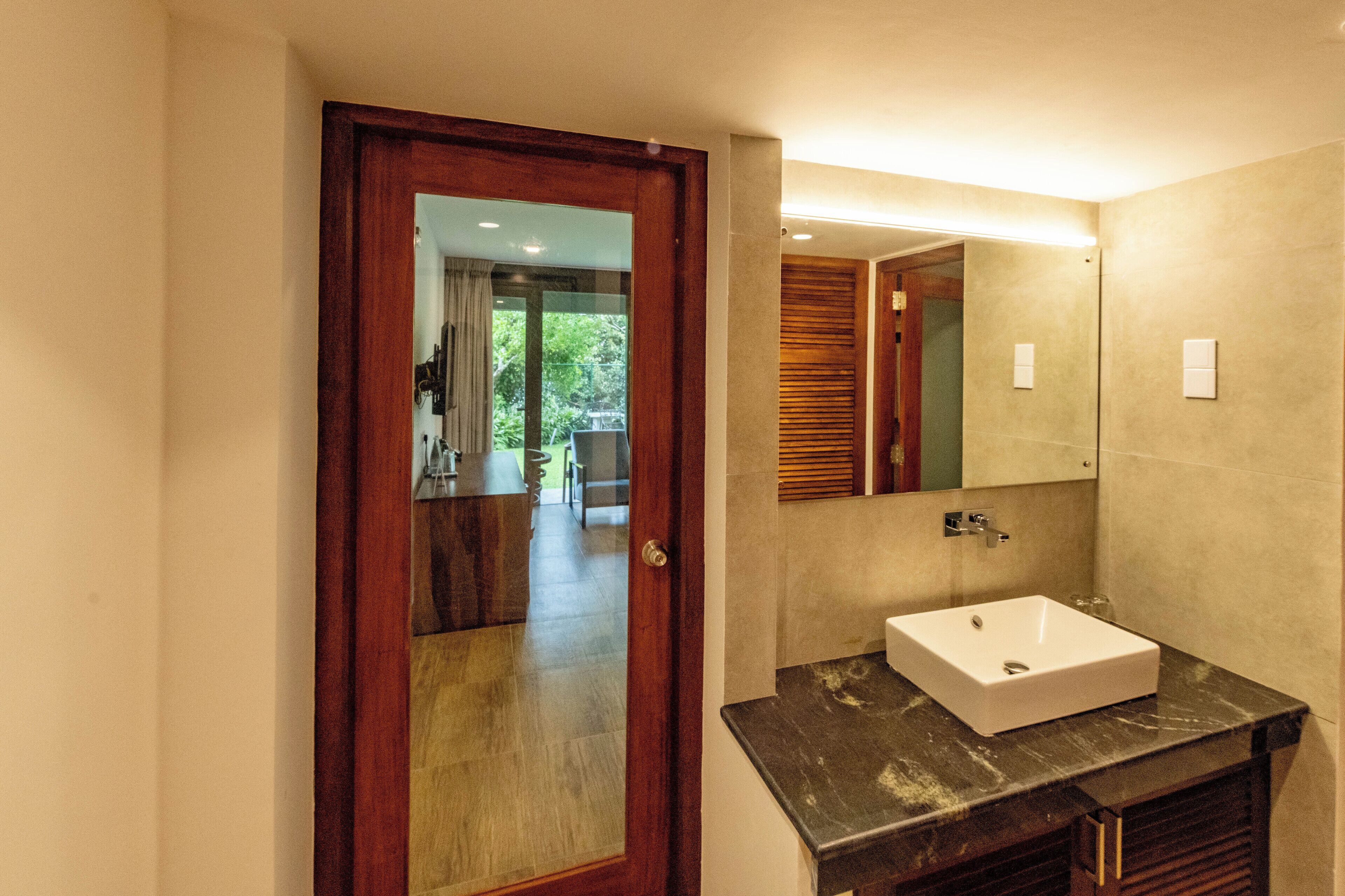 A bathroom with a wooden door, a white sink, and a mirror.