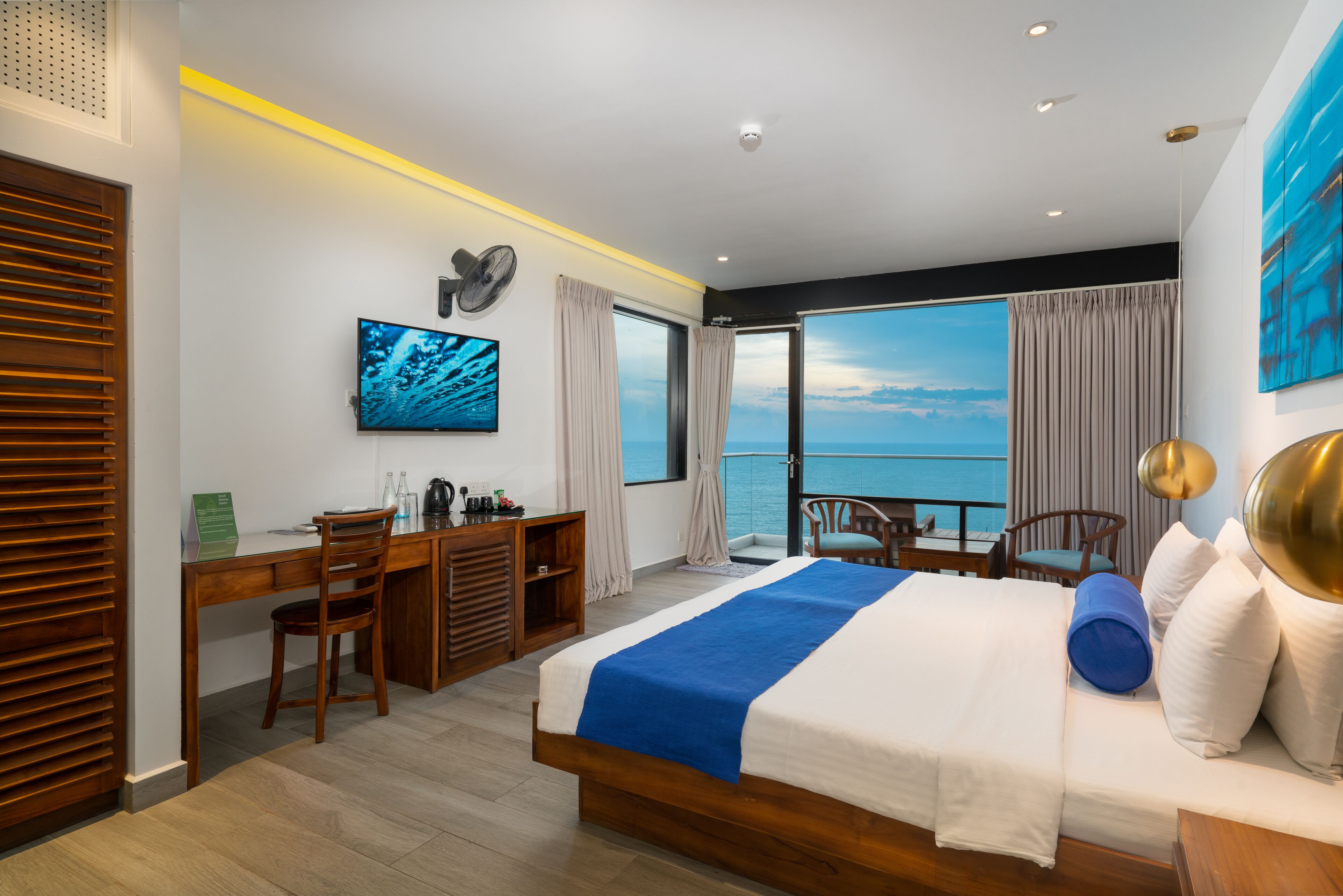 Een moderne hotelkamer met een groot bed, een bureau, een stoel en uitzicht op de oceaan.