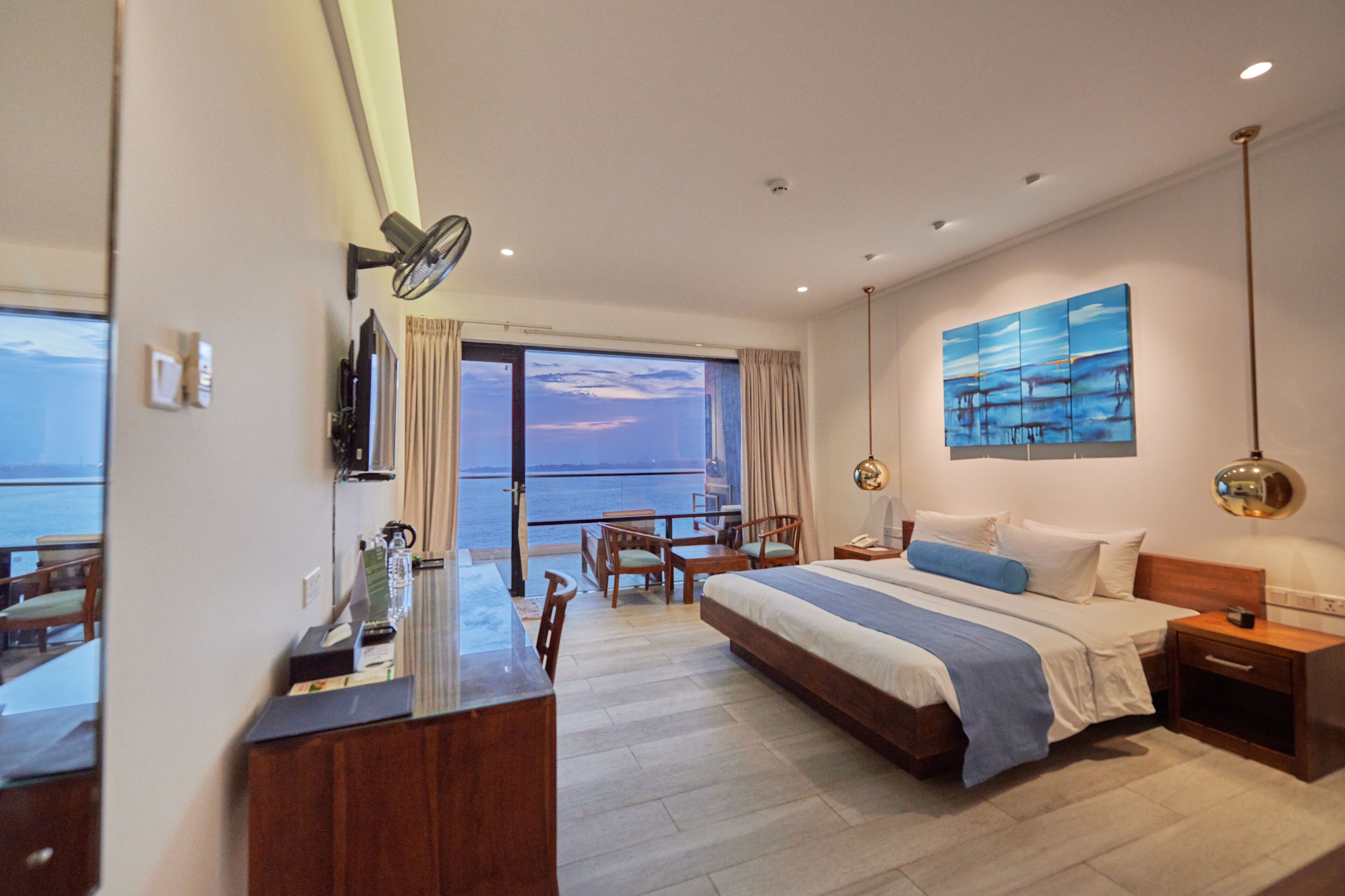Ein modernes Hotelzimmer mit einem großen Bett, einem Schreibtisch und Meerblick.