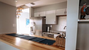 Una cocina moderna con encimeras de madera, electrodomésticos de acero inoxidable y armarios blancos.
