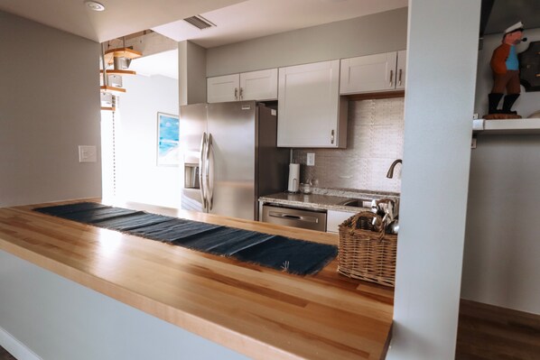 A modern kitchen with wooden countertops, stainless steel appliances, and white cabinetry.