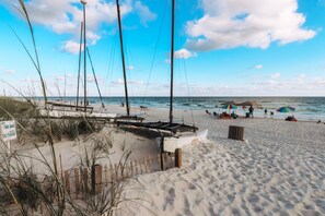 A beach with a wooden fence, a boat, and beach umbrellas.