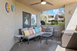 A covered patio with a sofa, coffee table, and grill area.