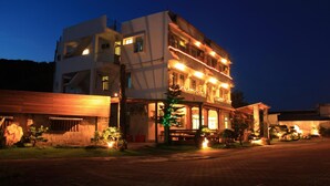 A multi-story hotel with a ground-level restaurant and a covered outdoor seating area. - Star-Moon B&B (Lyudao)