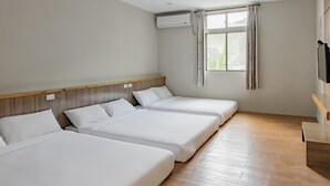 A hotel room with three single beds, a wooden headboard, a large window with curtains, an air conditioning unit, and a flat-screen TV mounted on the wall. - Star-Moon B&B (Lyudao)
