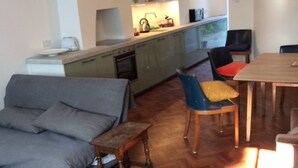 Una sala moderna con un sofá gris, una mesa de centro de madera y un comedor con mesa y sillas de madera.