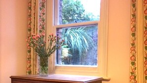 Un aparador de madera con cajones y un florero frente a una ventana con vistas al verdor.