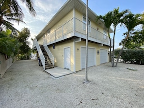 Ein zweistöckiges Gebäude mit Balkon, Treppe und zwei Garagenzufahrten.