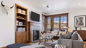 A living room with a fireplace, a television mounted above it, and a large window offering a view of the outside. - Outpost: Love Ridge 241 - Freestanding, AC! (Jackson)