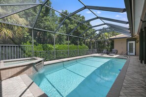 Une piscine dotée d’une enceinte en verre, entourée d’une terrasse dallée et d’un garde-corps en métal.