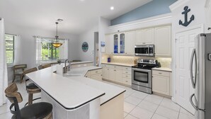A modern kitchen with white cabinetry, stainless steel appliances, and a central island. - 4Br Pristine Home Sleeps 6 Adu - Heated Pool + Spa - Private backyard (Marco Island)